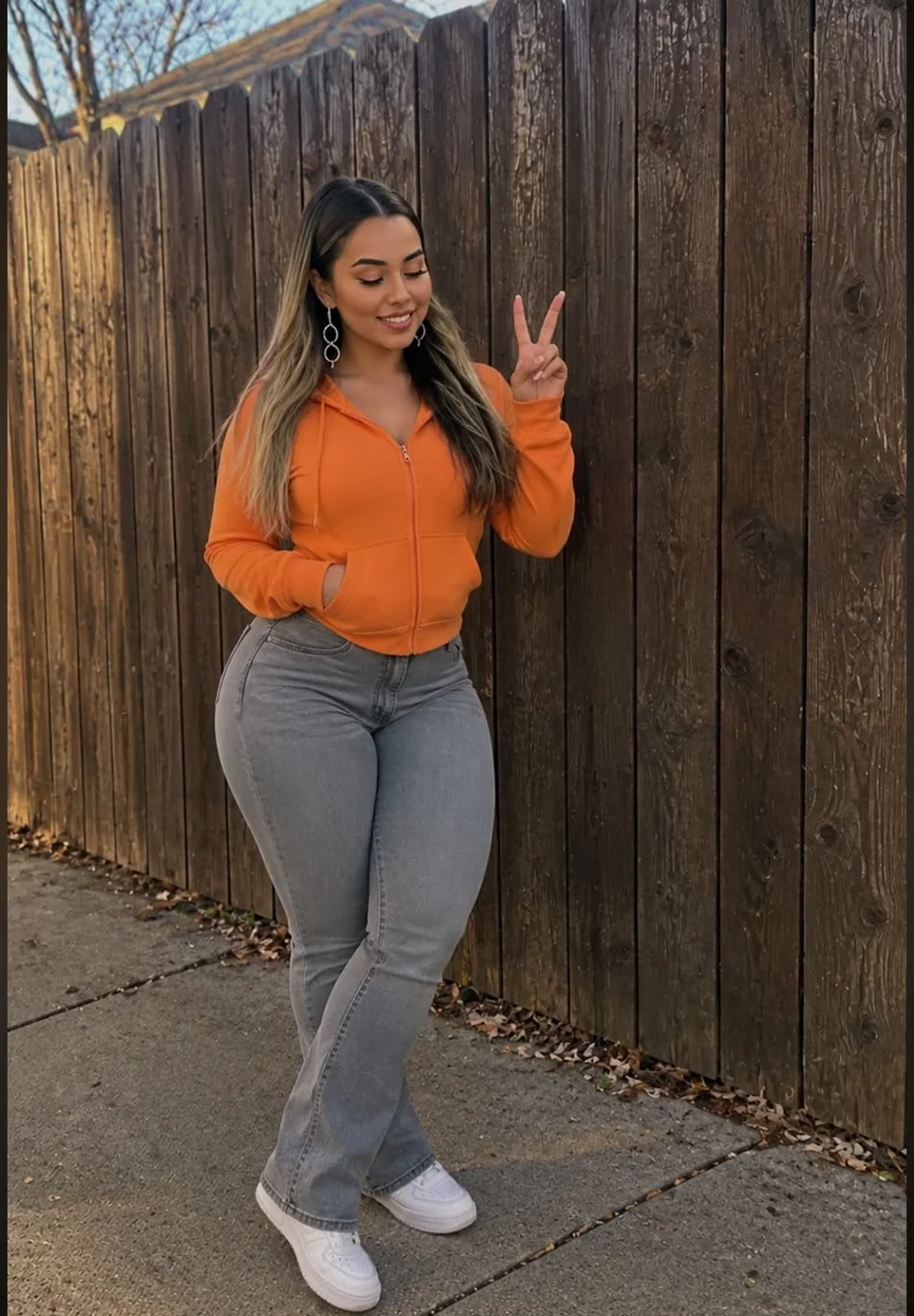 An orange hoodie and a peace sign beside a wooden fence